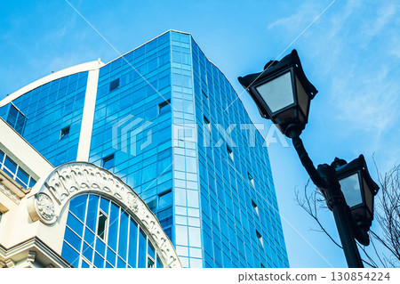 Part of the building with glazed windows against the sky and an old vintage streetlight Part of the building with glazed windows against the sky and an old vintage streetlight 130854224