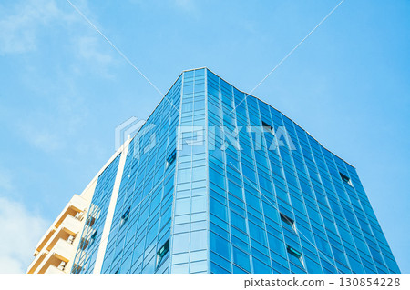 Part of the building with glazed windows against the sky Part of the building with glazed windows against the sky 130854228