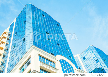 Part of the building with glazed windows against the sky Part of the building with glazed windows against the sky 130854229