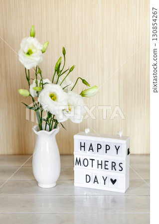 Light box with lettering Happy Mother's Day, white flowers Eustoma or Lisianthus in vase on wooden background with copy space Light box with lettering Happy Mother's Day, white flowers Eustoma or Lisianthus in vase on wooden background with copy space 130854267