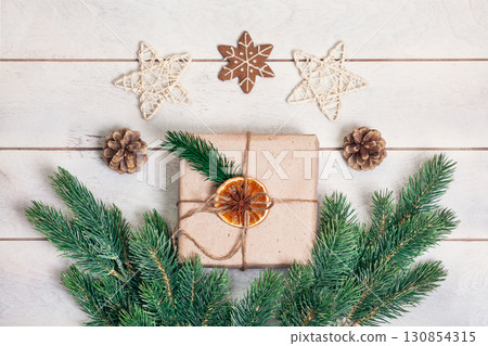 Gift boxed in eco friendly style: natural rough paper, rope of jute, spruce twigs on white wooden background 130854315