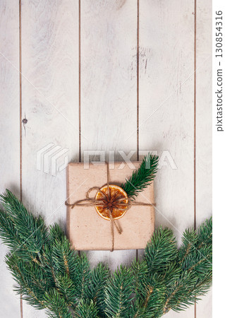 Gift boxed in eco friendly style: natural rough paper, rope of jute, spruce twigs on white wooden background 130854316
