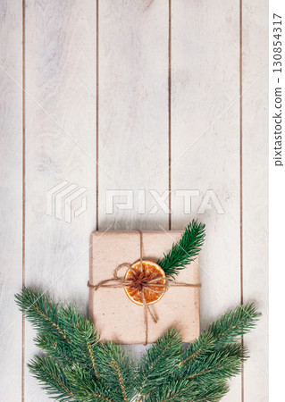 Gift boxed in eco friendly style: natural rough paper, rope of jute, spruce twigs on white wooden background 130854317