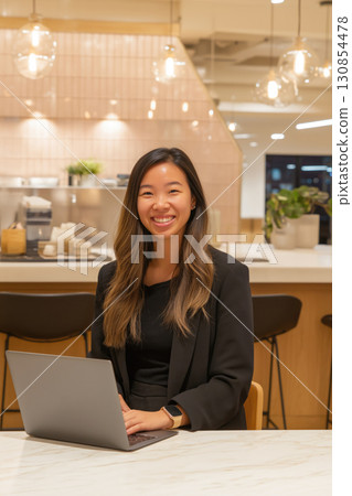 Smiling young woman at a modern workspace with laptop 130854478