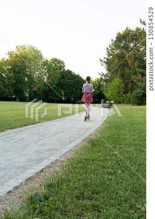 A child rides a scooter along the path 130854529