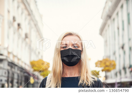 Woman in a black protective mask against background of the city. 130854790