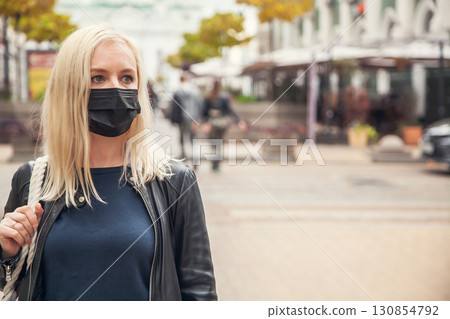 Woman in a black protective mask against background of the city 130854792