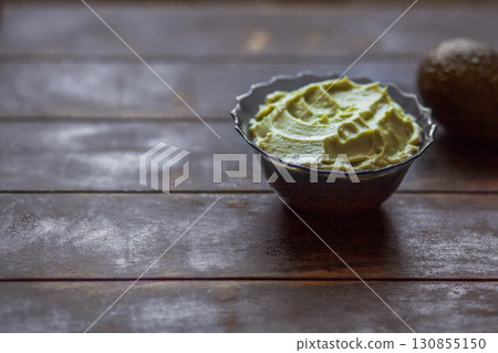 Traditional latinamerican mexican sauce guacamole in bowl and avocado on dark background with copy space 130855150