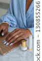 A closeup of a woman's hands typing on a laptop surrounded by white minimalist beauty products. 130855266