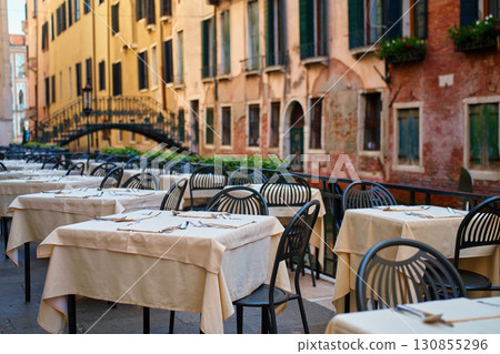Empty outdoor restaurant tables with cutlery in Venice, Italy 130855296
