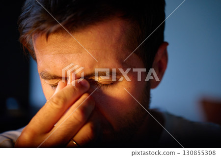 Tired man rubbing eyes in dark room 130855308