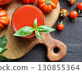 Fresh tomato juice in a glass and ripe tomatoes on the background. Tomato Fresh. Tomato juice and basil. 130855364