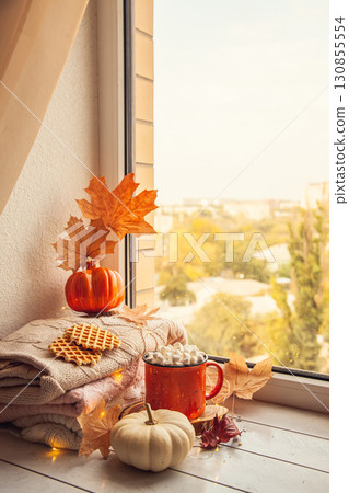 Cozy autumn still life on the windowsill: warm wool sweaters, pumpkins, maple leaves and a Cup of cocoa with marshmallows Cozy autumn still life on the windowsill: warm wool sweaters, pumpkins, maple leaves and a Cup of cocoa with marshmallows 130855554