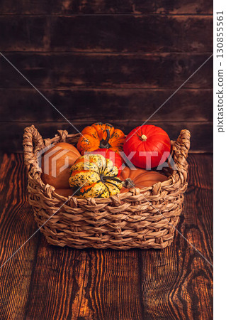 Basket with different varieties of pumpkin on a wooden background Basket with different varieties of pumpkin on a wooden background 130855561