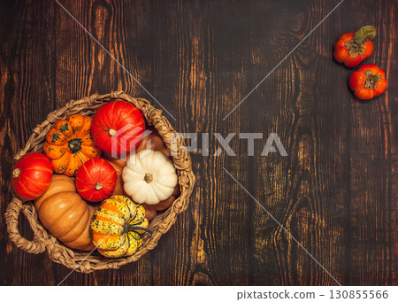 Basket with different varieties of pumpkin on a wooden background Basket with different varieties of pumpkin on a wooden background 130855566
