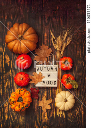 Flat lay Still life Autumn mood. Pumpkins, persimmon, wheat ears, maple leaves and lightbox on a brown wooden background Flat lay Still life Autumn mood. Pumpkins, persimmon, wheat ears, maple leaves and lightbox on a brown wooden background 130855571