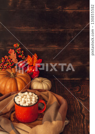 Autumn still life on a wooden background with cocoa mug and marshmallows, checkered scarf, pumpkins, leaves Autumn still life on a wooden background with cocoa mug and marshmallows, checkered scarf, pumpkins, leaves 130855582