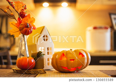 Kitchen decoration for Halloween: luminous cardboard house, candle, autumn leaves, jack-o-lantern Kitchen decoration for Halloween: luminous cardboard house, candle, autumn leaves, jack-o-lantern 130855589