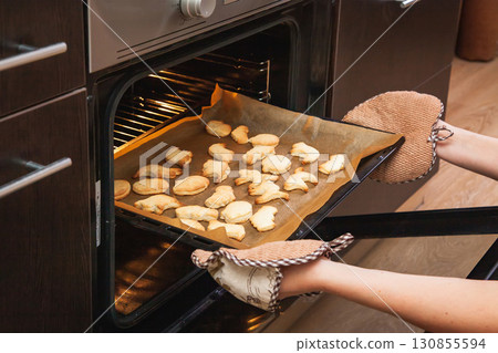Woman opens the oven where cookies are baked for Halloween 130855594