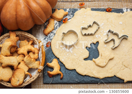 Making cookies for Halloween. Cut out cookies from dough in the form of pumpkin, cat, ghost and bat 130855600