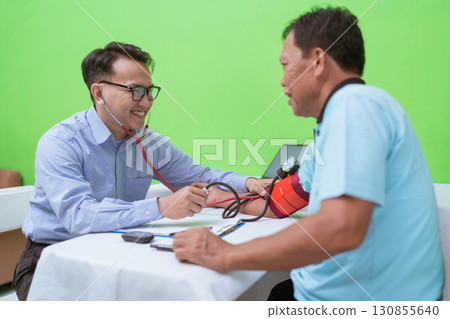 A doctor consults a patient during a health checkup in a bright, welllit room 130855640