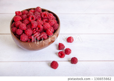 Raspberries in a coconut shell bowl on a white wooden background 130855662