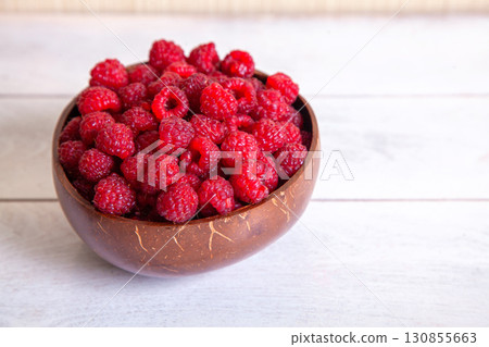 Raspberries in a coconut shell bowl on a white wooden background Raspberries in a coconut shell bowl on a white wooden background 130855663