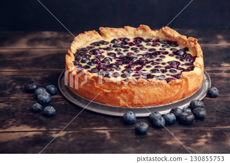 Rustic shortbread pie with blueberries in sour cream filling on a wooden background. 130855753