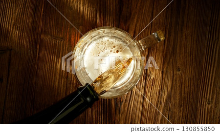 Pouring Beer into Pint Glass on Old Wooden Table, Top Down View. 130855850