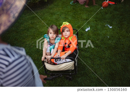 Children wearing Halloween costumes sitting in a wagon in the backyard Children wearing Halloween costumes sitting in a wagon in the backyard 130856160