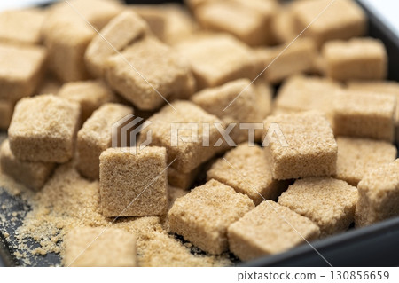 Organic brown sugar cubes in black bowl close up natural sweetener textured surface healthy ingredient rustic kitchen soft focus delicious and inviting Organic brown sugar cubes in black bowl close up natural sweetener textured surface healthy ingredient rustic kitchen soft focus delicious and inviting 130856659
