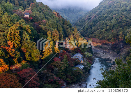 Early fog over Arashiyama valley Kyoto Japan with autumn trees buildings and Katsura River sunrise 130856870