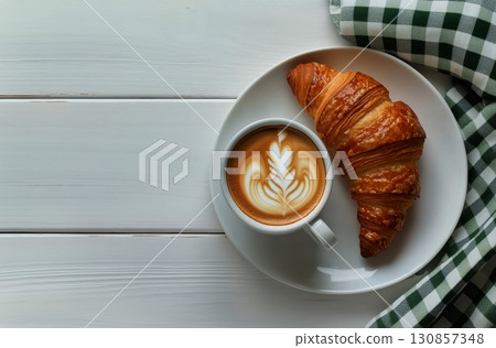 Warm Croissant and Latte on a Plate With Green Checkered Napkin at a Cozy Breakfast Table Setting 130857348