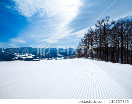 Beautiful corduroy patterns of packed snow spread across the slopes first thing in the morning (Togari Onsen, Iiyama City, Nagano Prefecture) 130857825