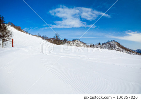 Groomed slopes and ski tracks under a blue sky (Togari Onsen, Iiyama City, Nagano Prefecture) 130857826