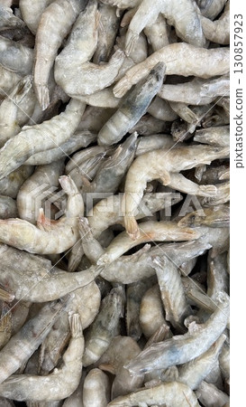 Frozen shrimp closeup showing raw seafood texture, ideal for culinary backgrounds and recipes Frozen shrimp closeup showing raw seafood texture, ideal for culinary backgrounds and recipes 130857923