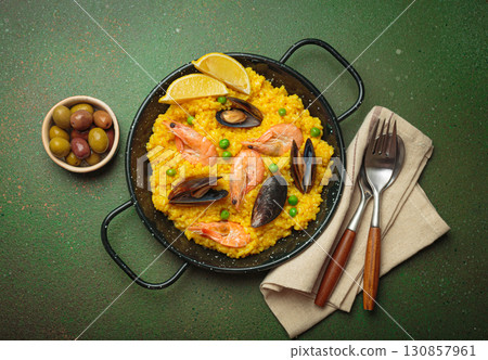 Spanish seafood Paella with shrimps, mussels, peas and lemon in a pan on green rustic background top view Spanish seafood Paella with shrimps, mussels, peas and lemon in a pan on green rustic background top view 130857961