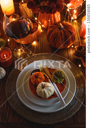 Autumnal table setting with decorative pumpkins, candles and string lights. 130858085
