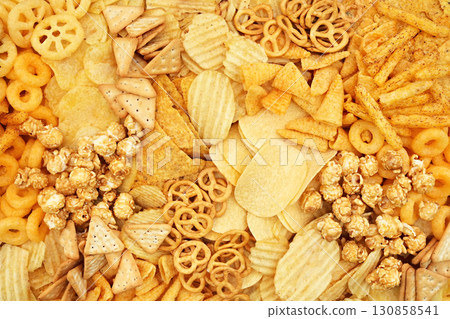 Colorful mix of salty snacks for beer varieties: chips and pretzels, rings and crackers. Non-healthy junk food background 130858541