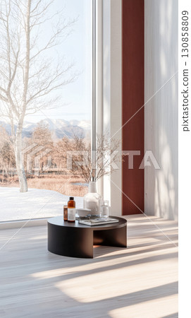Modern indoor space featuring a stylish coffee table by a large window with a winter view of mountains and a snowy landscape Modern indoor space featuring a stylish coffee table by a large window with a winter view of mountains and a snowy landscape 130858809