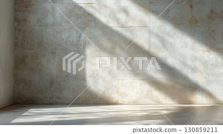 Natural light casts long shadows on a textured wall in a minimalist interior space during the afternoon 130859211