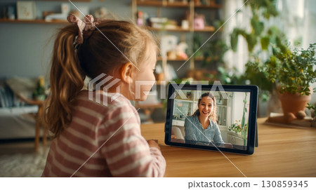 Little girl talking on video call on tablet with smiling woman at home 130859345