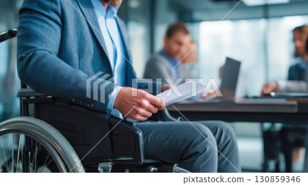 Businessman in wheelchair holding documents during office meeting, close-up of inclusive workspace and corporate diversity Businessman in wheelchair holding documents during office meeting, close-up of inclusive workspace and corporate diversity 130859346