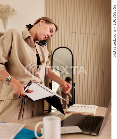 Professional multitasking at a home office workspace with notebooks and laptop Professional multitasking at a home office workspace with notebooks and laptop 130859358