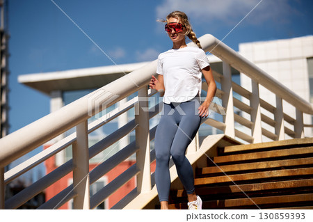 Athletic woman jogging on a sunny day wearing stylish fitness outfit 130859393