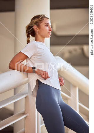 Active woman in sportswear leaning on railing after exercising outdoors Active woman in sportswear leaning on railing after exercising outdoors 130859402
