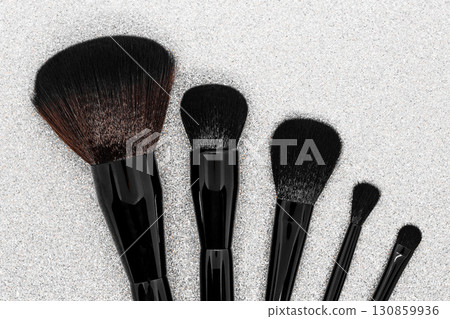 Black and brown makeup brushes on shiny silver background surface Black and brown makeup brushes on shiny silver background surface 130859936