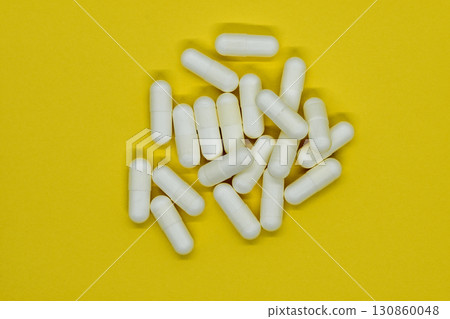 Bunch of white medication pills on yellow background surface Bunch of white medication pills on yellow background surface 130860048