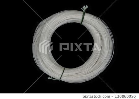 Bundle of white, very old and dusty fishing line on black background surface Bundle of white, very old and dusty fishing line on black background surface 130860050