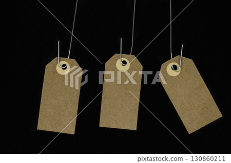 Hanging blank brown note cards with copy space hooked on metal spring and isolated on black background Hanging blank brown note cards with copy space hooked on metal spring and isolated on black background 130860211